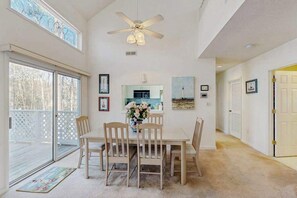 A dining area with a table, chairs, a ceiling fan, and a view through large windows. - Sea Colony Tennis 2nd-floor condo w/community pools, tennis/pickleball, gym (Bethany Beach)
