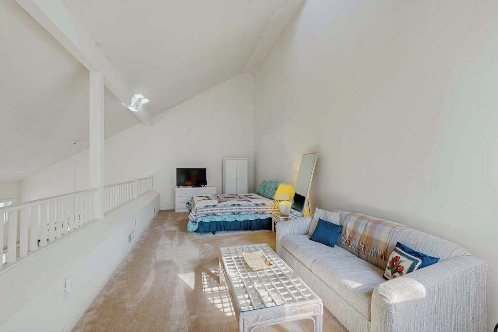 A spacious room with a bed, a sofa, a TV, and a staircase.