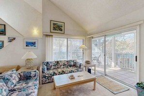 A living room with a sofa, a coffee table, and a view of a balcony. - Sea Colony Tennis 2nd-floor condo w/community pools, tennis/pickleball, gym (Bethany Beach)