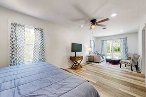 A bedroom with a bed, a TV, a ceiling fan, and a window with patterned curtains. - Town of Millville - 32669 Cedar Drive | House in Millville (Millville)