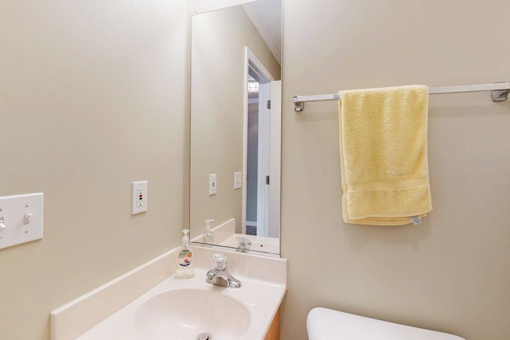 A bathroom with a sink, mirror, towel rack, and toilet.