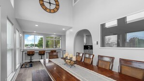 A dining room with a long wooden table, chairs, a decorative runner, and a wall clock. - The Lone Star Lakehouse at Eagle Mountain Lake (Azle)