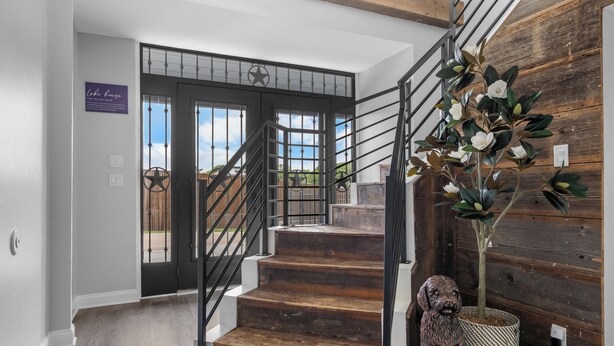 A staircase with wooden steps and black railings, leading to a door with a star-shaped window grille. - The Lone Star Lakehouse at Eagle Mountain Lake (Azle)