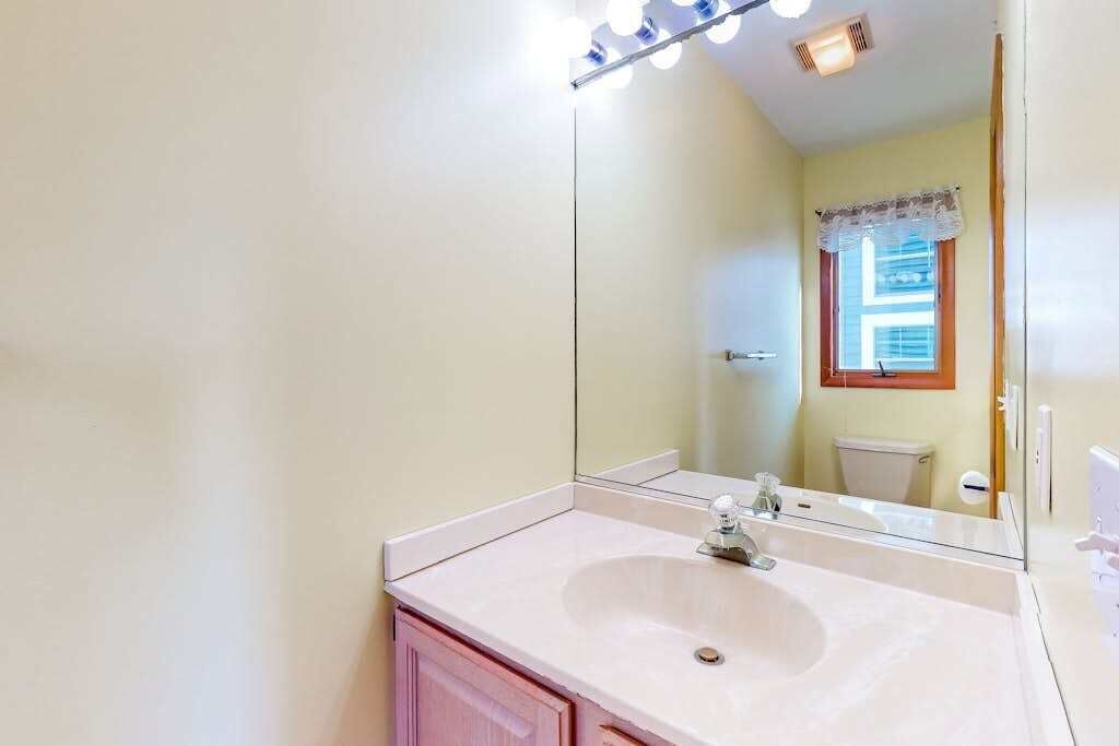 Une salle de bain avec un lavabo, un miroir et des luminaires.