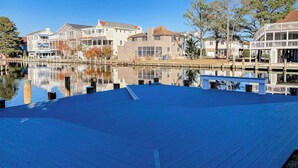 Una proprietà fronte lago con una terrazza in legno, un lago calmo e palazzi residenziali sullo sfondo.