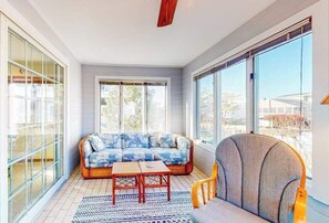 A sunlit room with a sofa, a chair, and a table. - Town of South Bethany enchanting canal-front retreat with decks & amazing views (Bethany Beach)