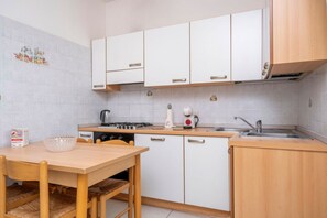 Een keuken met witte kasten, een houten tafel en een spoelbak.