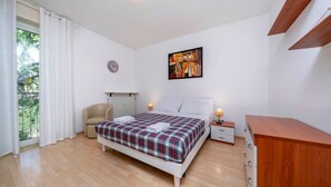 A bedroom with a bed, bedside tables, a chair, a wooden dresser, a painting on the wall, and a window with curtains. - A comfortable and welcoming 60 square meters apartment, perfect for four people, located on the fourth floor of a period building without an elevator.The property is located in a quiet area, allowing our guests to easily and quickly reach the center of U (Udine)