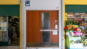 A wooden door with a metal handle, a sign above it, and a flower display outside. - A comfortable and welcoming 60 square meters apartment, perfect for four people, located on the fourth floor of a period building without an elevator.The property is located in a quiet area, allowing our guests to easily and quickly reach the center of U (Udine)
