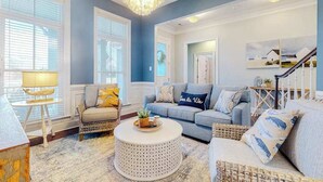 A living room with a blue wall, a round coffee table, a sofa, and a chandelier. - Dazzling Bayside Resort home with pools, gym, & athletic court - close to beach (Selbyville)