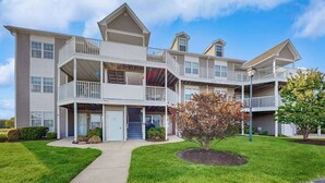 A multi-story residential building with balconies, a covered front porch, and a well-maintained lawn. - 2nd-floor Bethany Bay condo with waterfront views & on-site golf/pool/tennis (Ocean View)