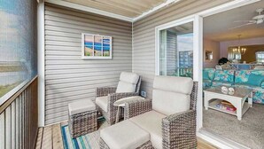 A covered patio with wicker furniture, a view of the interior, and a framed picture on the wall. - 2nd-floor Bethany Bay condo with waterfront views & on-site golf/pool/tennis (Ocean View)