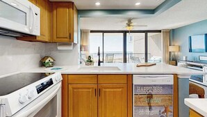 A modern kitchen with wooden cabinets, a microwave, an oven, and a large island with a sink. - Sea Colony Ocean beachfront condo with 12 pools, sauna, tennis, private beach (Bethany Beach)