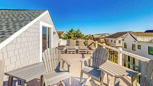 Ein Balkon mit Adirondack-Stühlen und einem Tisch, mit Blick auf eine Wohngegend mit Häusern.