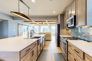 A modern kitchen with a central island, built-in appliances, and a view to the living area. - Bay Views - Walk to Beach - Multiple Decks - Pets Welcome! (Bethany Beach)