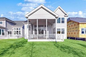 A two-story house with a covered porch, a fenced yard, and a neighboring house under construction. - Marlin Chase home with resort amenities, bikes, grill, EV charger - dog-friendly (Ocean View)