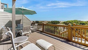 A wooden deck with outdoor furniture, a green umbrella, and a view of the ocean. - Kings Grant Beachfront Townhouse w/Ocean Views, Shared Pool, Free WiFi, Private (Fenwick Island)