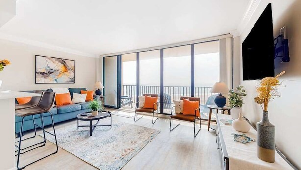 A modern living room with a sofa, chairs, a coffee table, and a large window. - Enjoy views, resort amenities & a spacious condo for perfect beach retreat (Bethany Beach)
