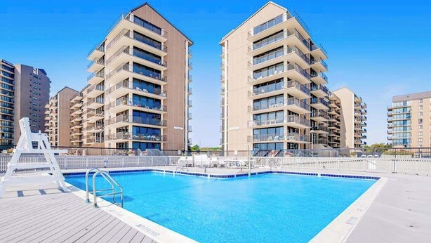 Une piscine entourée d’immeubles d’habitation à plusieurs étages et dotée d’une terrasse en bois.