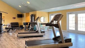 Ett gym med löpband, vikter och en spegel.
