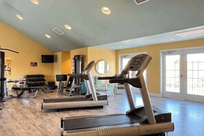 Ein Fitnessraum mit Laufbändern, Gewichten und einem Spiegel.