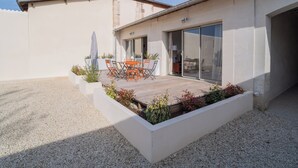Een modern huis met terras, een eettafel en stoelen.