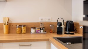 Een keuken met een houten aanrecht, potten met pasta en kruiden, een koffiezetapparaat en een waterkoker.