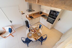 Una cocina compacta con electrodomésticos modernos, una mesa de comedor con sillas y un pequeño rincón de estar.