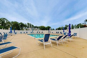 A poolside area with lounge chairs and umbrellas, a swimming pool, and a white fence. - Updated Waterside home near beach with screened deck & community pool (Frankford)