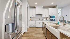 A modern kitchen with white cabinets, stainless steel appliances, and a wooden floor. - Stingray Harbor condo with W/D, WIFI, close to restaurants (Ocean View)