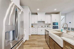 Eine moderne Küche mit weißen Schränken, Edelstahlgeräten und Holzboden.