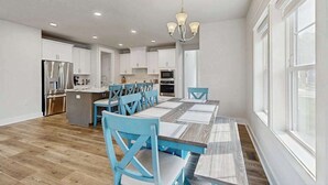 A spacious kitchen with white cabinets, a central island, and a dining area with blue chairs and a wooden table. - Stingray Harbor condo with W/D, WIFI, close to restaurants (Ocean View)
