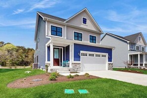 Ein zweistöckiges Haus mit Garage, überdachter Veranda und gepflegtem Rasen.