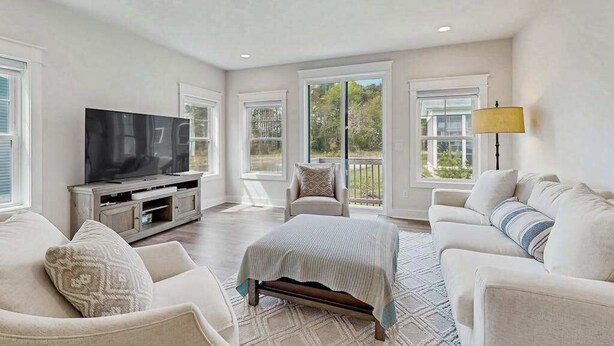 A spacious living room with a flat-screen TV, a sofa set, a chair, and a bed. - Stingray Harbor condo with W/D, WIFI, close to restaurants (Ocean View)