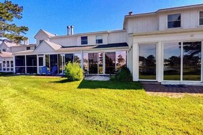Una casa moderna de dos pisos con un porche cubierto, un césped cuidado y un gran ventanal corredera.