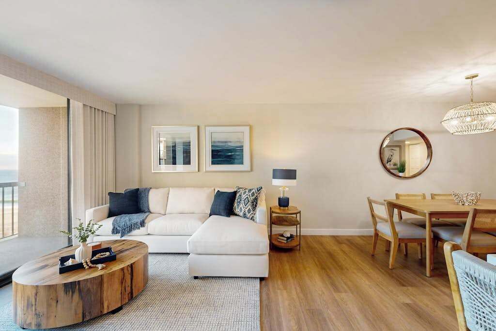 Een moderne woonkamer met een bank, salontafel, eettafel en een kroonluchter.