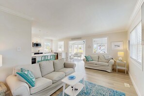Ein modernes Wohnzimmer mit zwei Sofas, einem Couchtisch und einer Küche im Hintergrund.