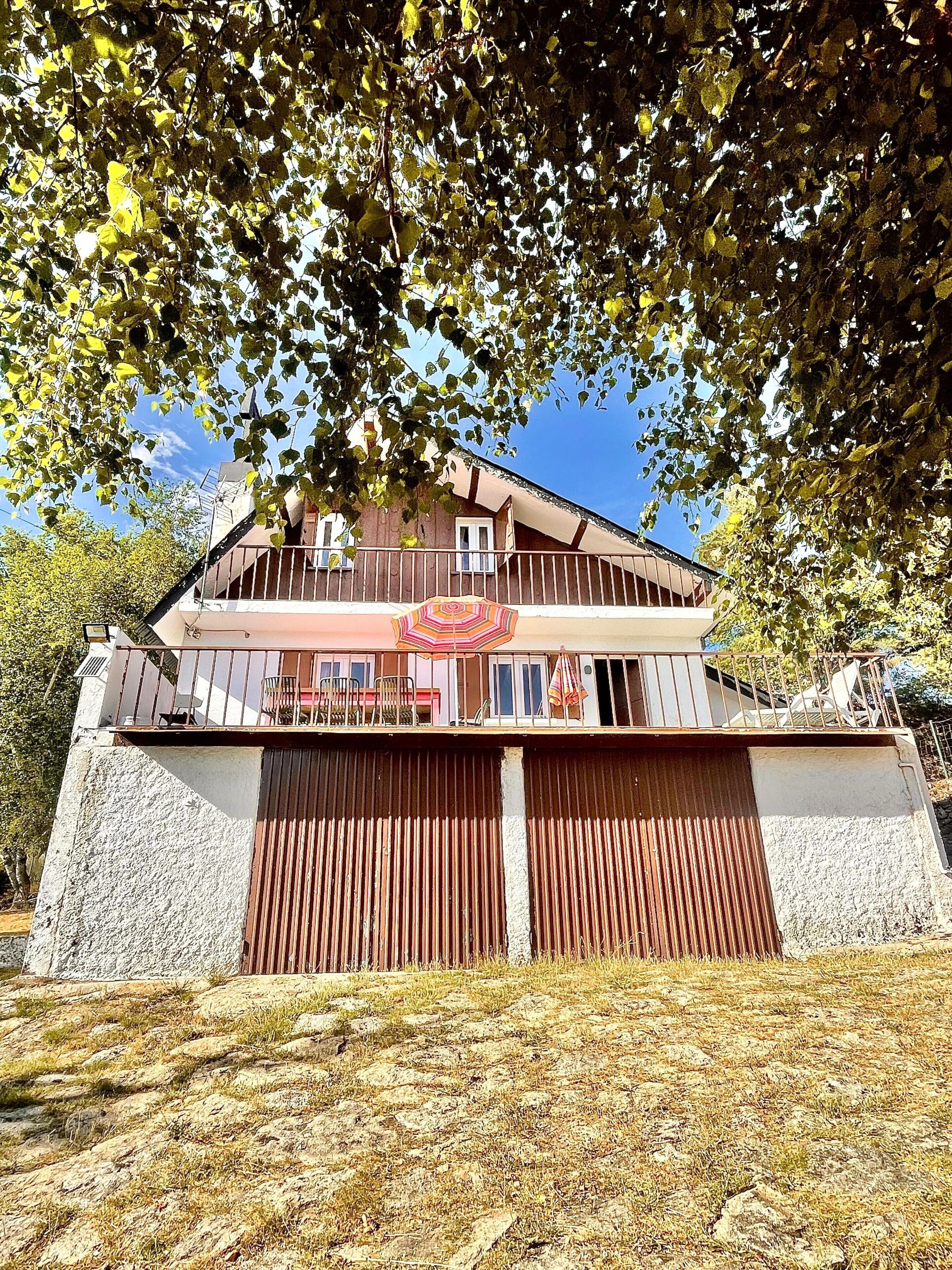 Ein zweistöckiges Gebäude mit Balkon, Garage und einer Steinmauer.