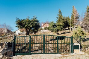 A gated area with a stone wall, a wooden house, and trees.