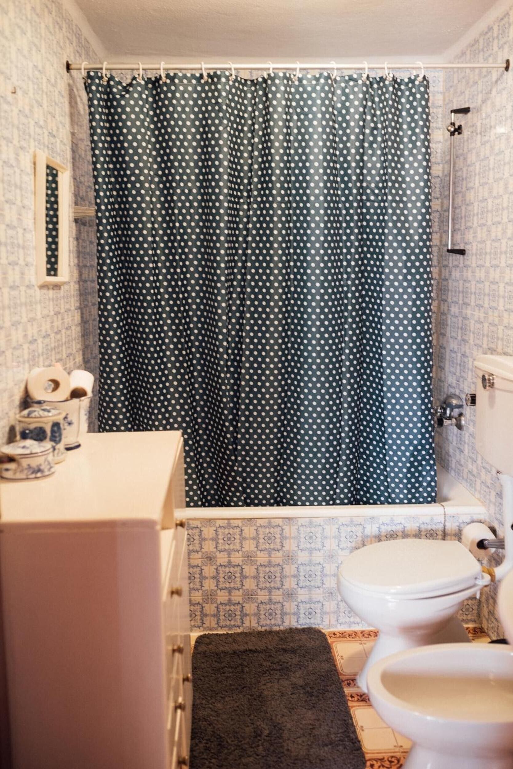 A bathroom with a polka dot shower curtain, a toilet, and a sink with a towel.
