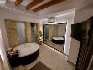 Ein modernes Badezimmer mit einem großen Spiegel, einer Badewanne und einem Fernseher.