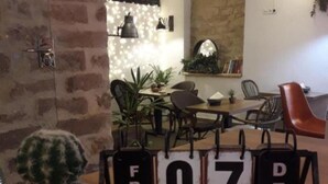 A room with a brick wall, a cactus, a table with chairs, and a wall-mounted calendar displaying the date. - Deluxe Compact Flat With Jacuzzi (Alicante)