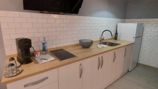 A kitchen with white tiled backsplash, a flat-screen TV mounted above the counter, a coffee maker, a bowl, and a refrigerator. - Deluxe Compact Flat With Jacuzzi (Alicante)