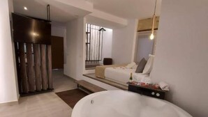 A modern bathroom with a freestanding bathtub, a seating area with a sofa, and a large mirror. - Deluxe Compact Flat With Jacuzzi (Alicante)