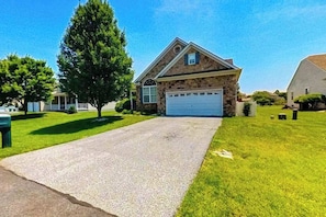 A residential house with a stone facade, a garage, and a well-maintained lawn. - Wedgefield dog-friendly house w/community pool, patio & gas grill (Ocean View)