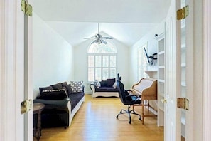A room with a ceiling fan, a piano, a sofa, and a window with blinds. - Wedgefield dog-friendly house w/community pool, patio & gas grill (Ocean View)