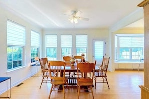 A dining area with a table and chairs, large windows, and a ceiling fan. - Wedgefield dog-friendly house w/community pool, patio & gas grill (Ocean View)