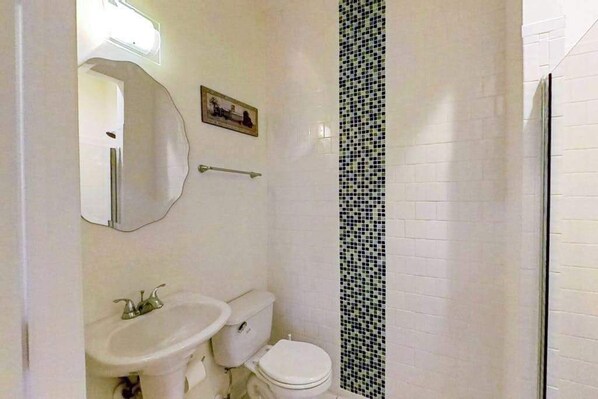 A bathroom with a toilet, sink, and mirror. - Wedgefield dog-friendly house w/community pool, patio & gas grill (Ocean View)