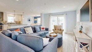 A modern living room with a sectional sofa, a round ottoman, and a patterned armchair. - Spacious home w/community boat launch, dock, patio, W/D, & AC (Selbyville)