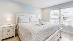A bedroom with a bed, nightstands, a window, and a view of buildings. - Spacious home w/community boat launch, dock, patio, W/D, & AC (Selbyville)